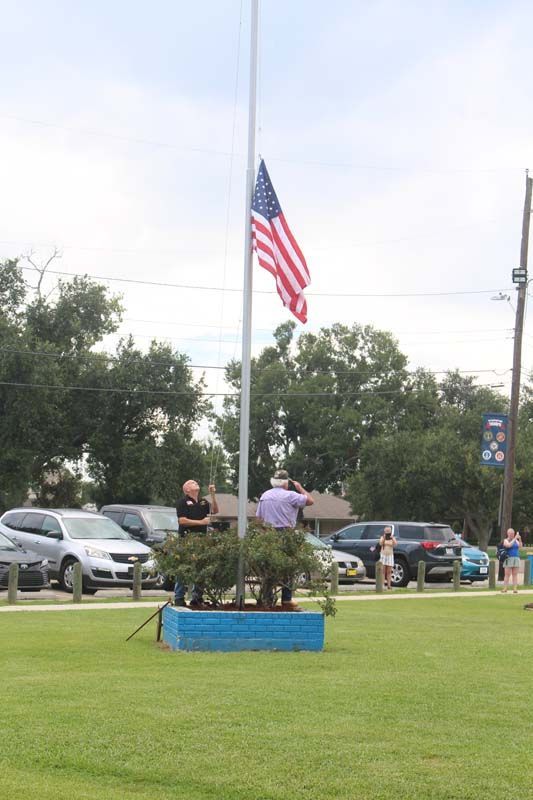 A man stands in front of an american flag on a pole