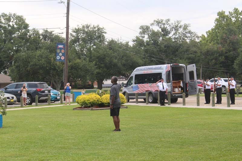 A man is standing in front of an ambulance in a park.