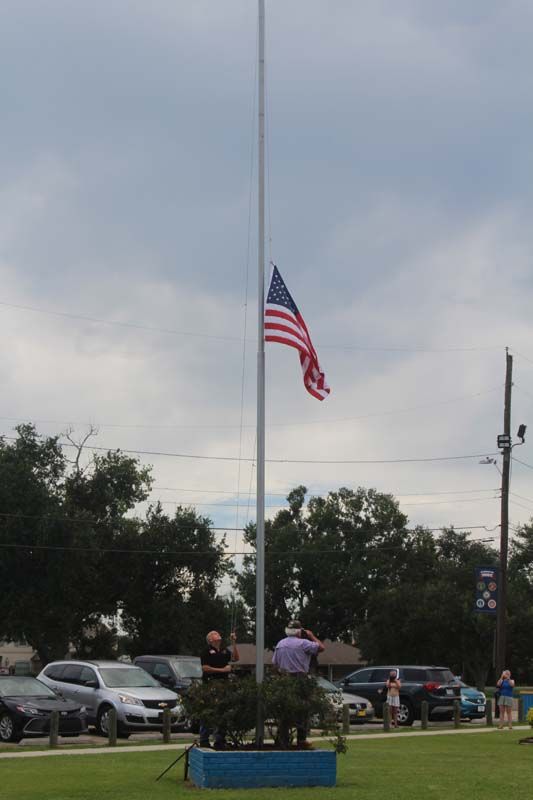 An american flag is flying on a pole in a parking lot