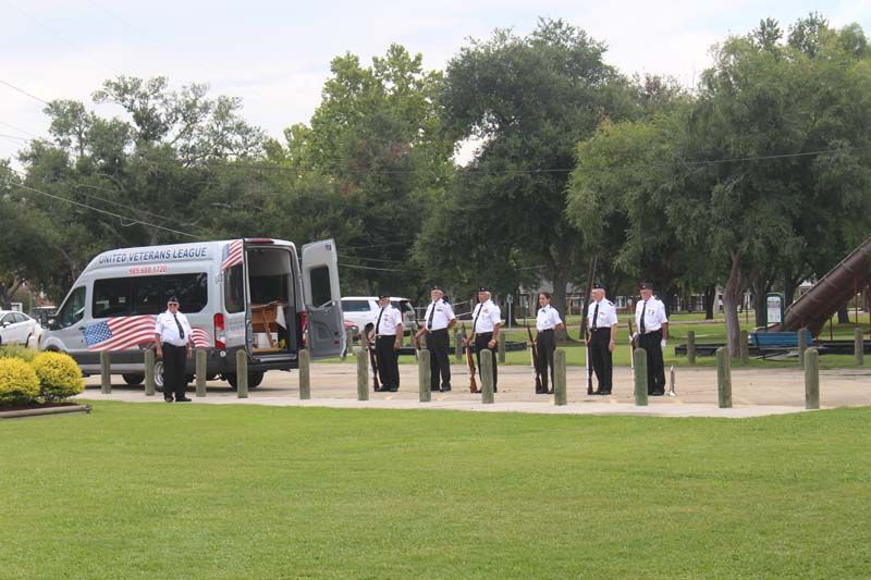 A group of men standing in front of an ambulance in a park.