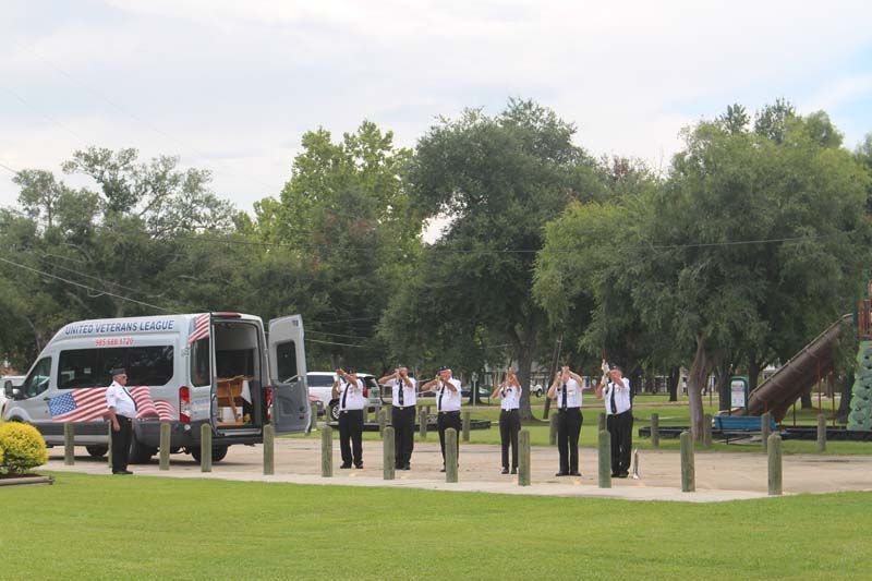 A group of men are standing in front of an ambulance in a park.