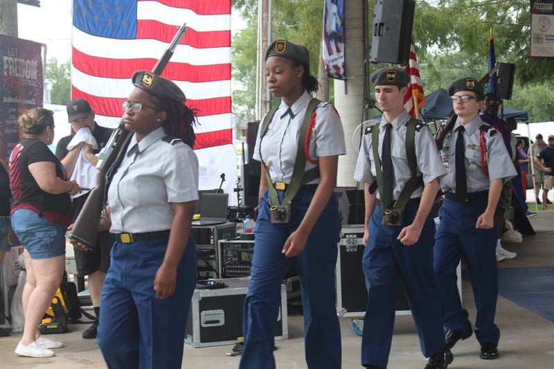 A group of soldiers marching in front of an american flag