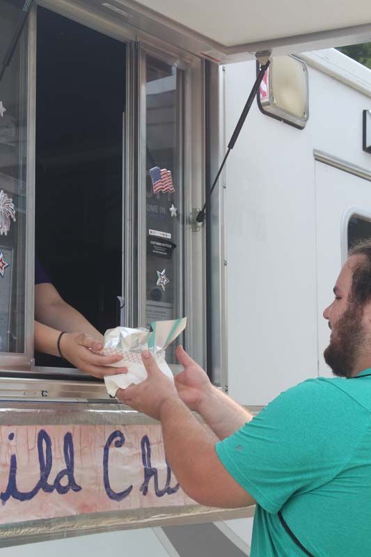 A man in a green shirt is getting food from a food truck