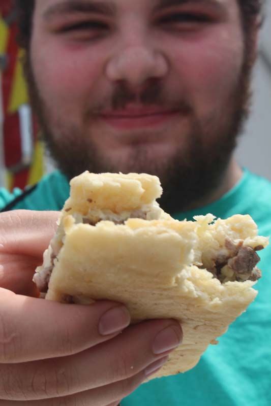 A man with a beard is holding a piece of food in his hand