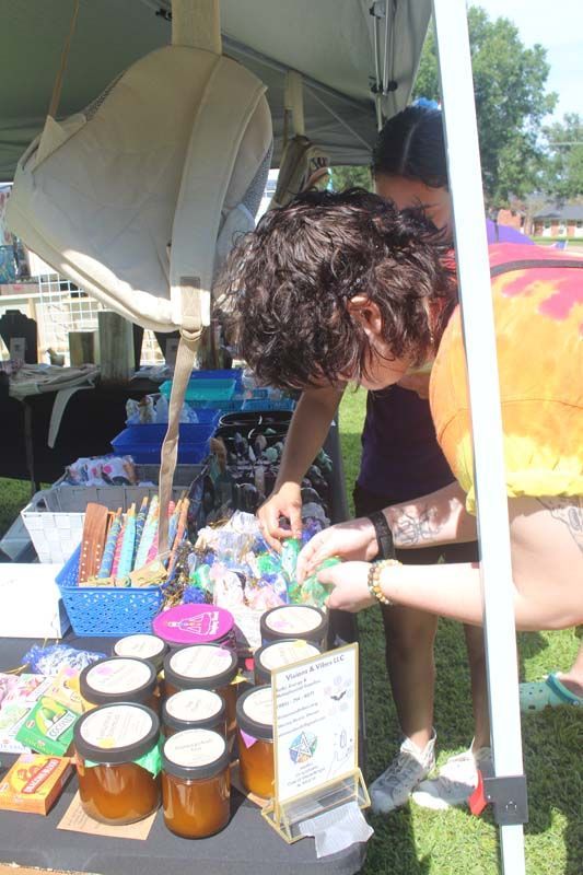 A woman is looking at jars of honey on a table.