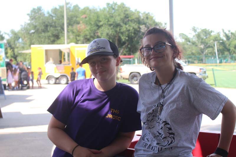Two girls are posing for a picture in front of a yellow truck.