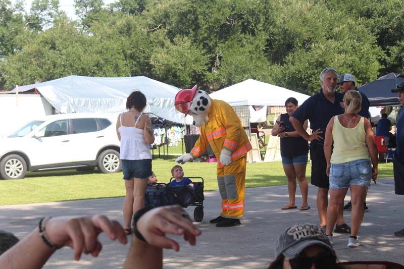 A man in a fireman costume is standing in front of a crowd of people.