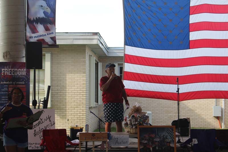 A woman is speaking into a microphone in front of an american flag.