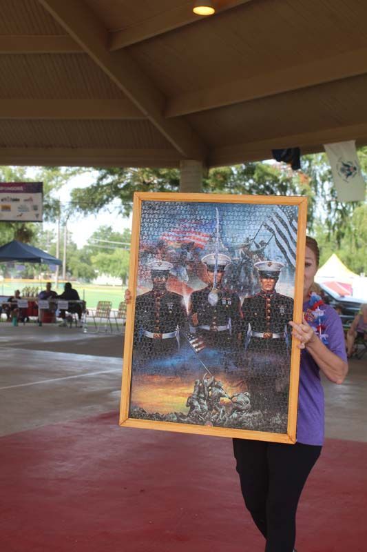 A woman in a purple shirt is holding a framed picture of marines