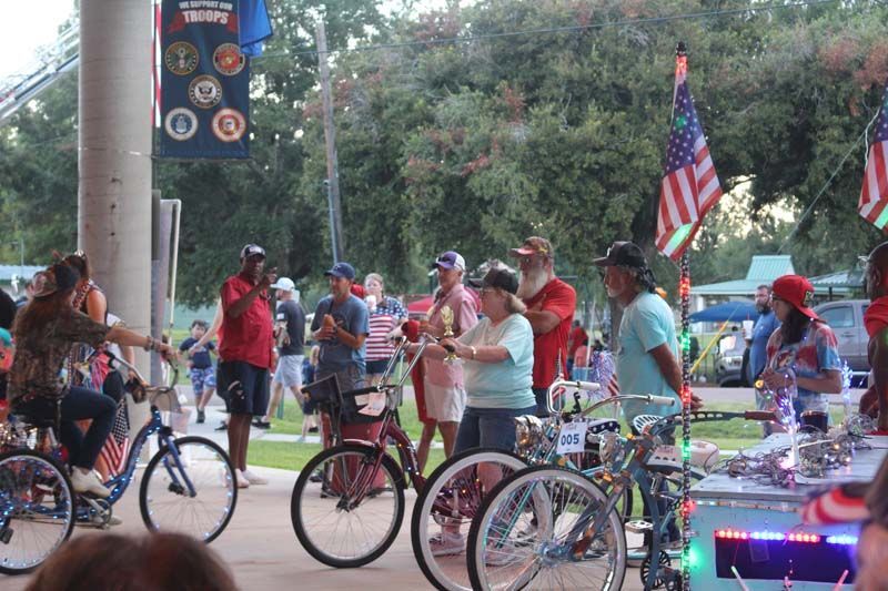 A group of people are standing around bicycles in a park.