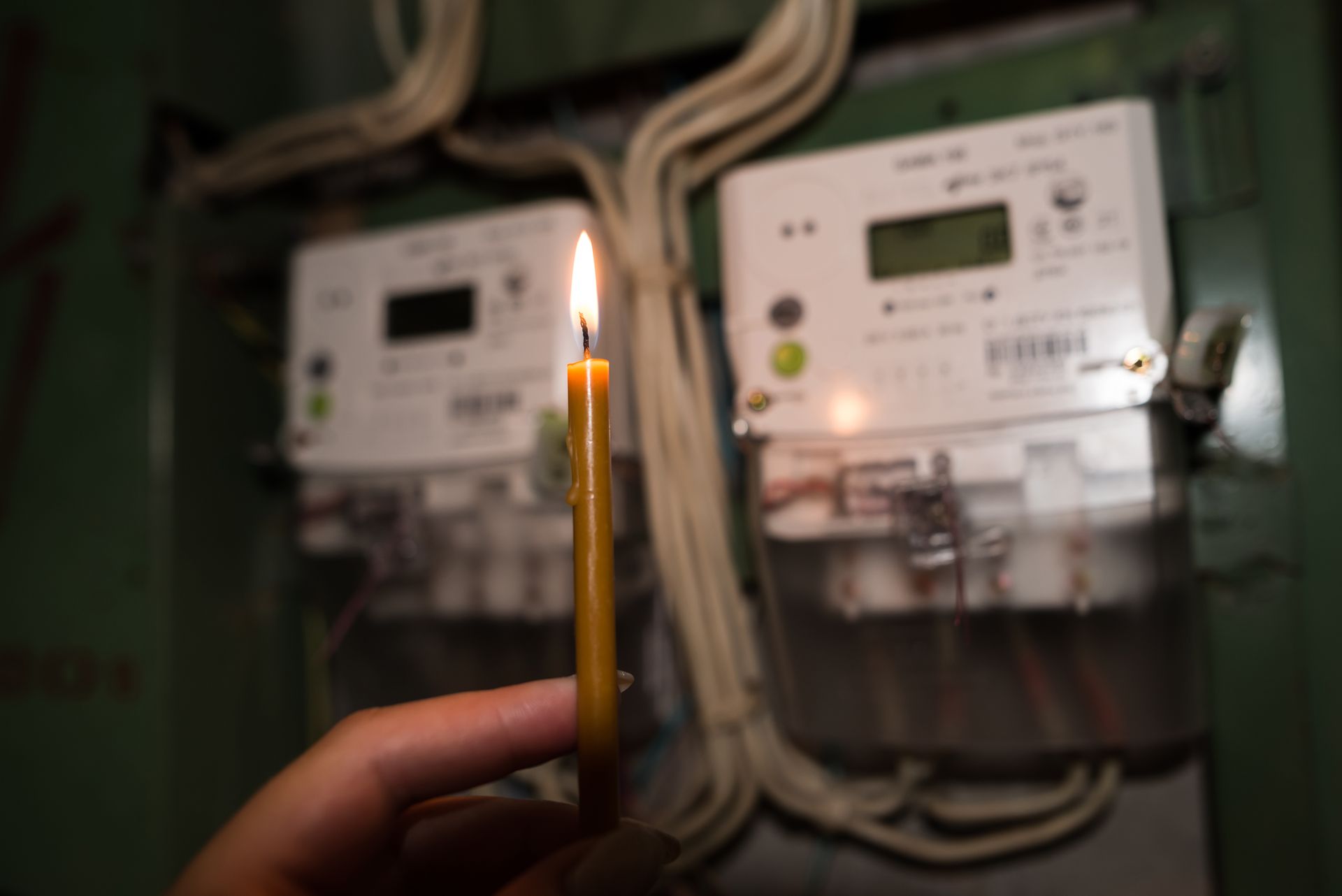 A person is holding a lit candle in front of a meter.