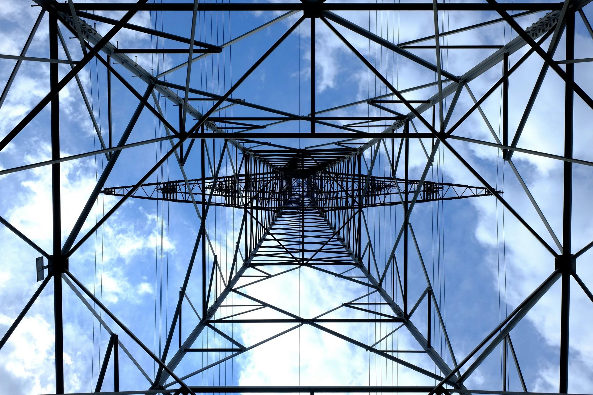 Looking up at a power tower with a blue sky in the background