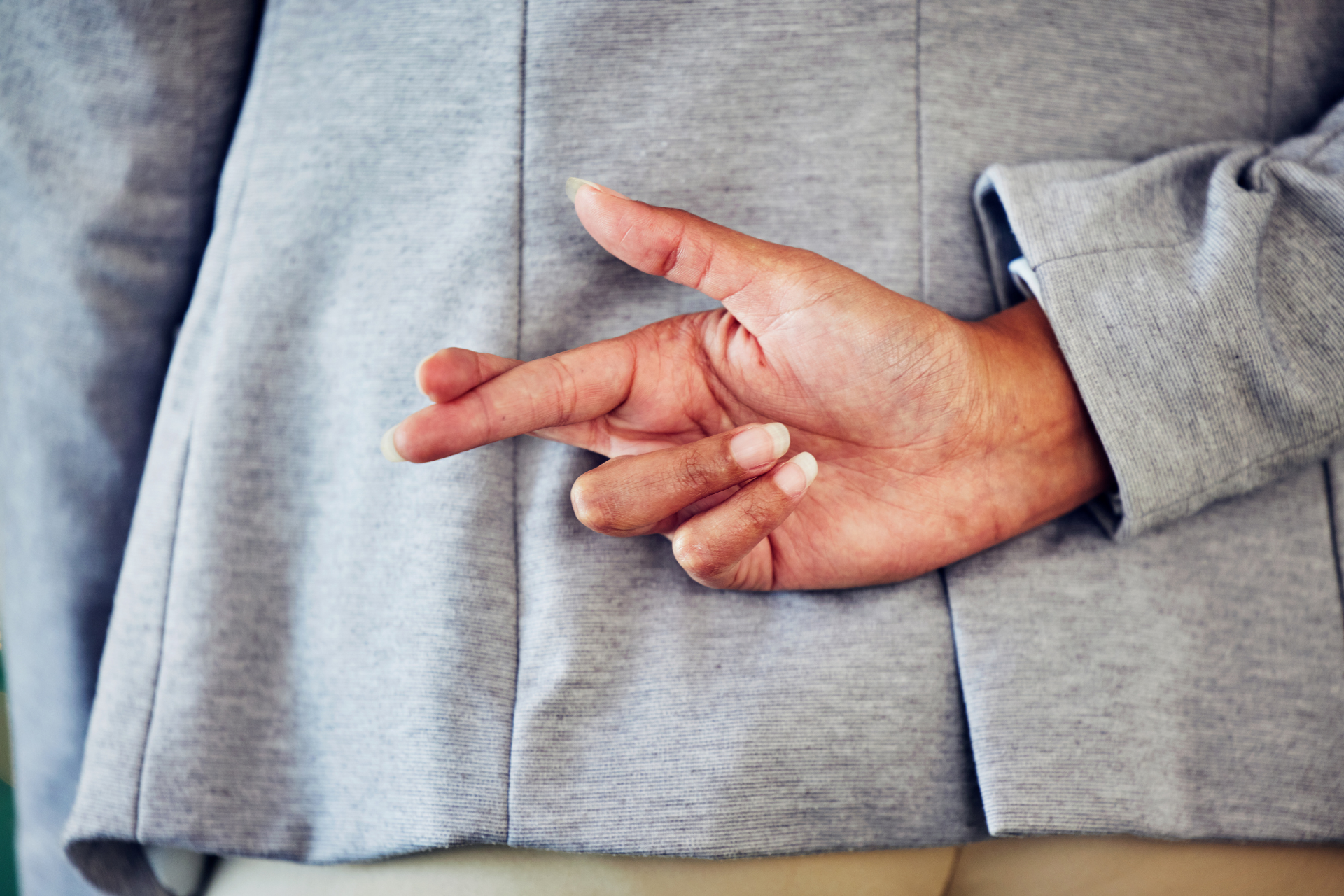 A person crossing their fingers behind their back