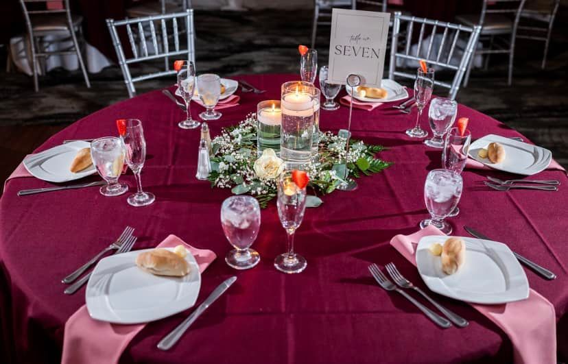 A table set for a wedding reception with plates, glasses, and candles