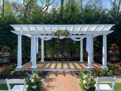 A wedding ceremony is taking place under a white pergola