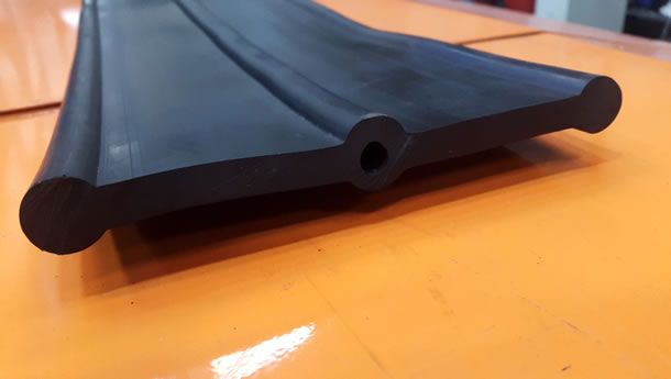 Sobre una mesa hay una tira de goma negra con un agujero en el medio.