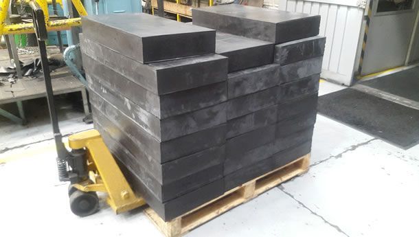 Una carretilla amarilla transporta una plataforma de bloques negros.