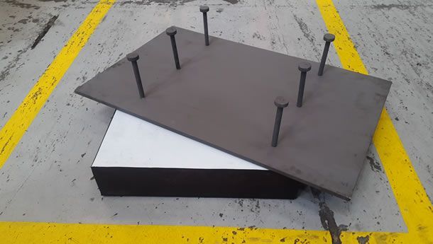 Un trozo de metal con clavos está sobre una línea amarilla.