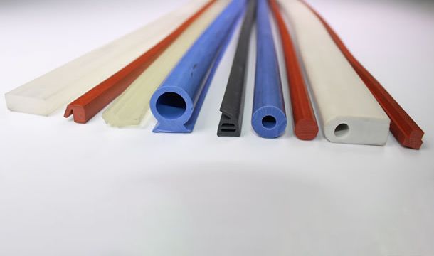 Un montón de tubos de goma de diferentes colores están alineados sobre una superficie blanca.