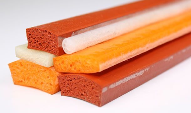 Un montón de palos de goma de diferentes colores están apilados uno encima del otro sobre una superficie blanca.