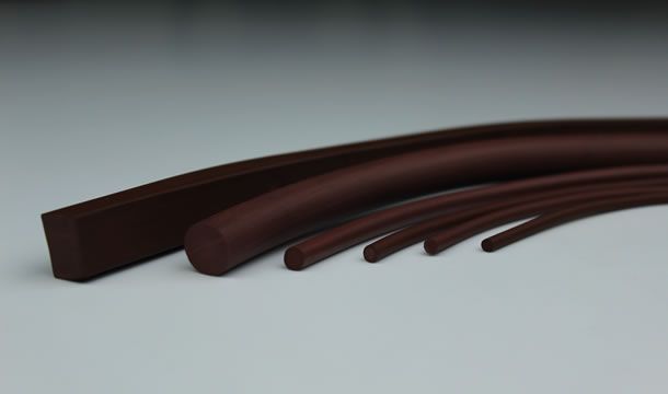 Un grupo de cuerdas de goma marrones están colocadas una encima de la otra sobre una superficie blanca.