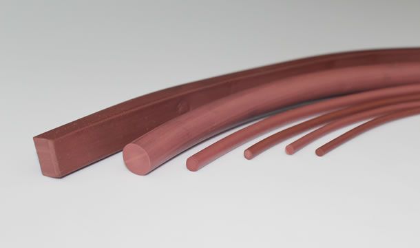 Un grupo de tubos de goma rojos están colocados uno encima del otro sobre una superficie blanca.