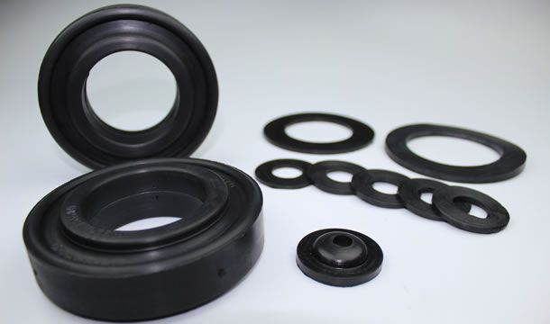 Un montón de sellos de goma y arandelas sobre una superficie blanca