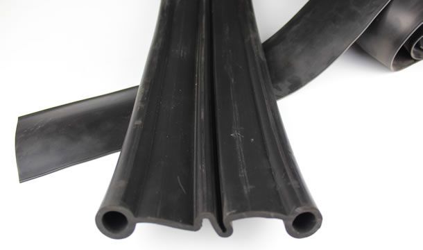 Un primer plano de una manguera de goma negra sobre una superficie blanca.