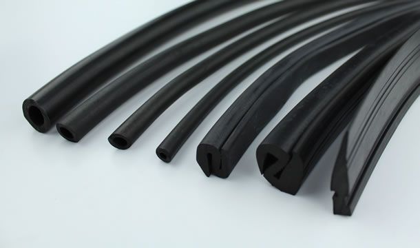 Un montón de tubos de goma negros están colocados uno encima del otro sobre una superficie blanca.