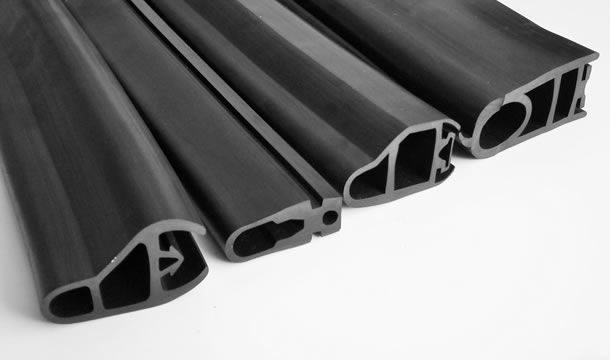 Un montón de tubos de goma negros están apilados uno encima del otro sobre una superficie blanca.