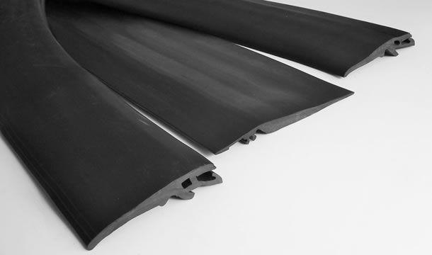 Un primer plano de tres tiras de goma negras sobre una superficie blanca.