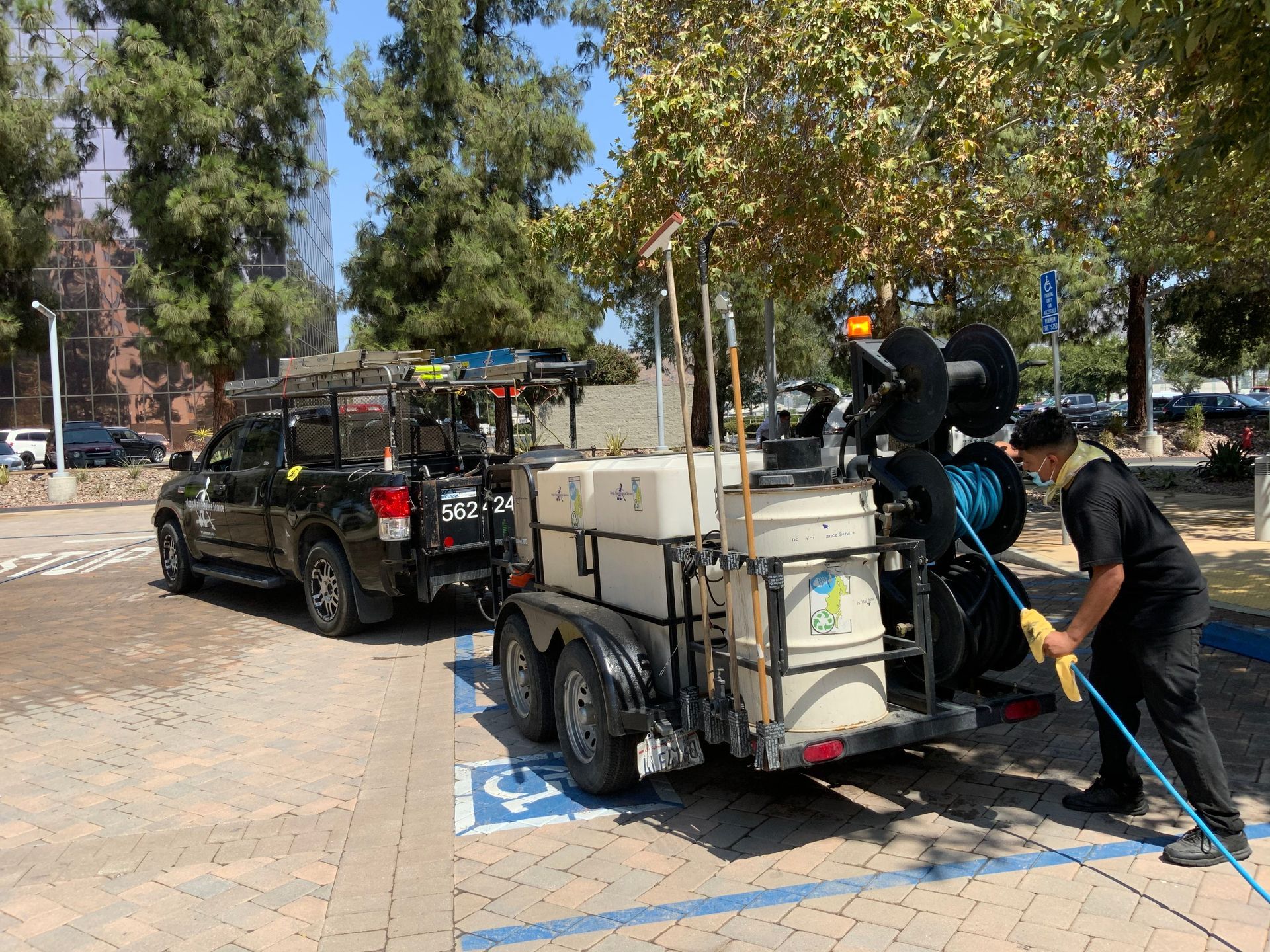 A man is standing next to a trailer with a hose attached to it.