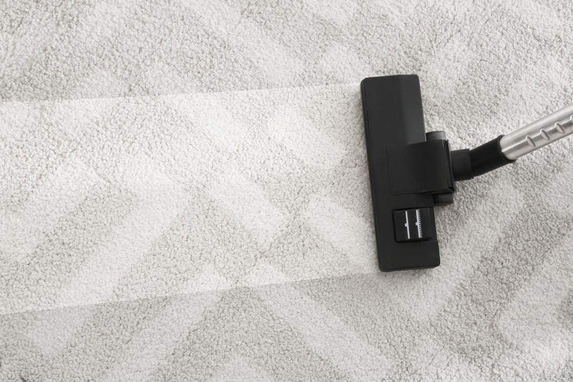 A person is using a vacuum cleaner to clean a carpet.