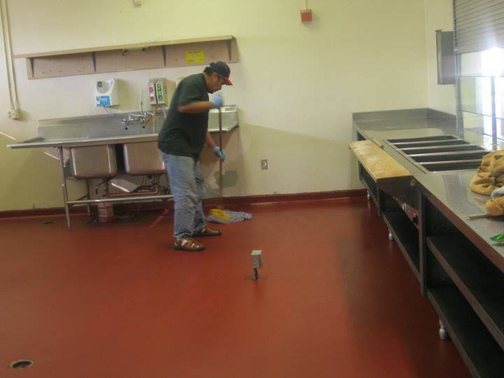 A man cleaning a kitchen floor with a mop