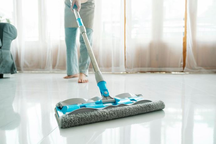 A woman is cleaning the floor with a mop in a living room.