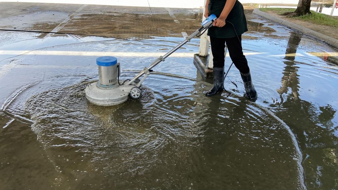 A woman is cleaning a puddle of water with a machine.