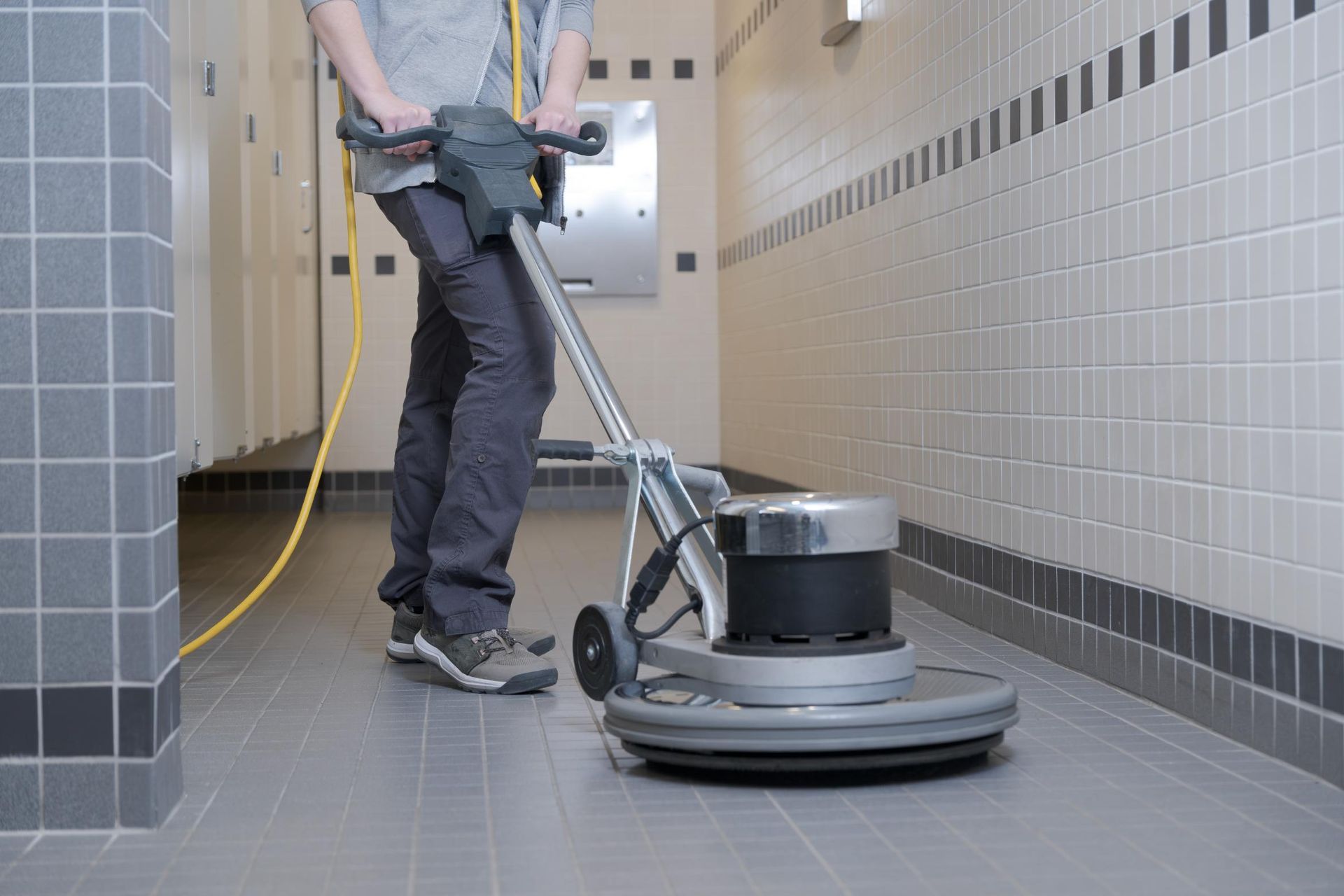 A person is cleaning a tiled floor with a machine.