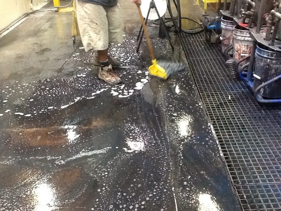 A person is cleaning a dirty floor with a broom.