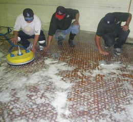 Three men are cleaning a tiled floor with a machine