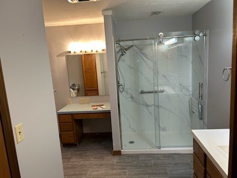 Bathroom with a white marble-look shower, a vanity with drawers, and gray walls.