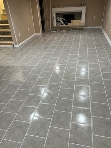 Gray tiled floor in a room with a fireplace and stairs.