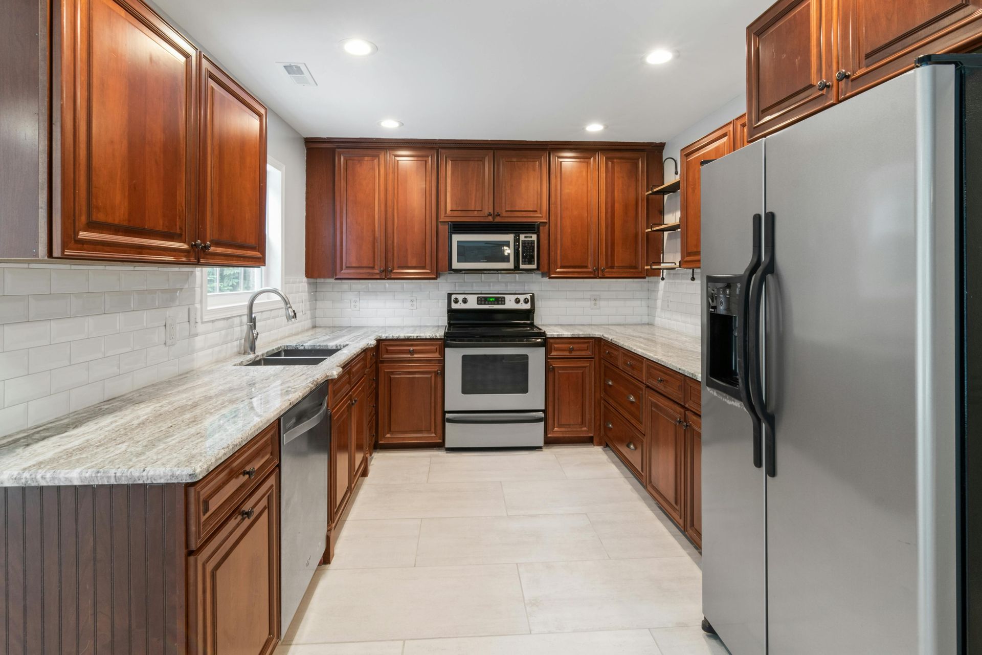 U-shaped kitchen with brown cabinets, stainless steel appliances, and granite countertops.