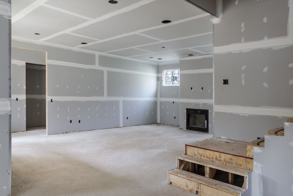 Interior room under construction with gray drywall and exposed framing.