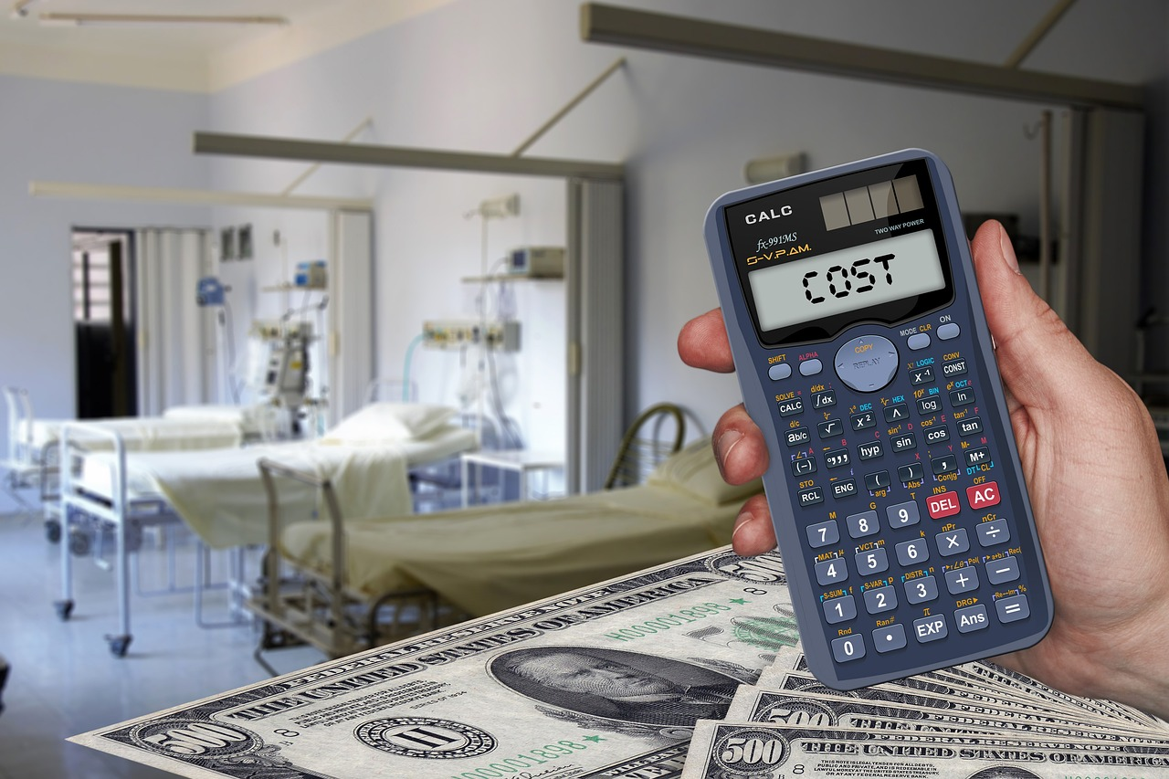 A person is holding a calculator in front of a hospital room.