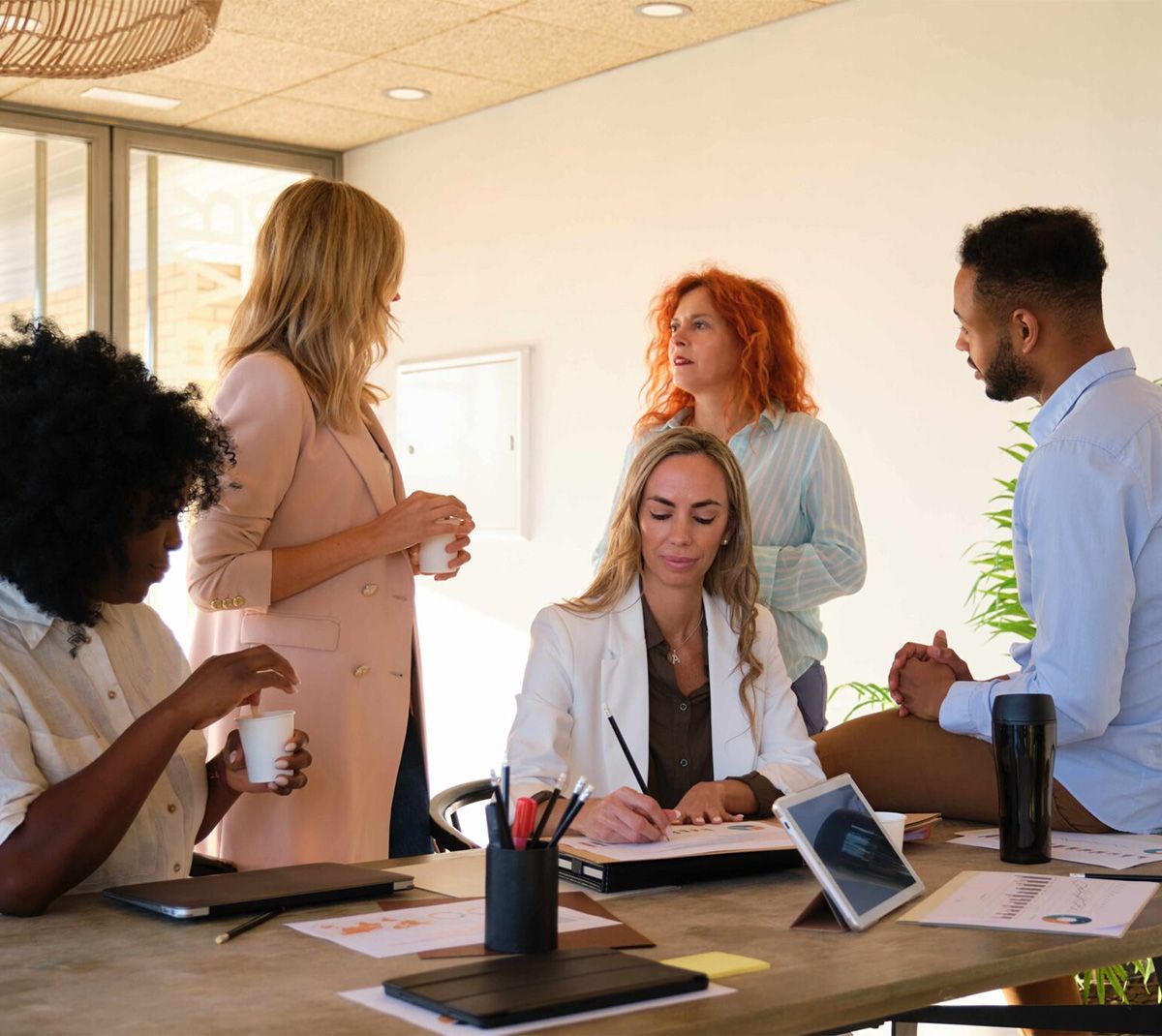 A group of interracial people are gathering around a table having a meeting.