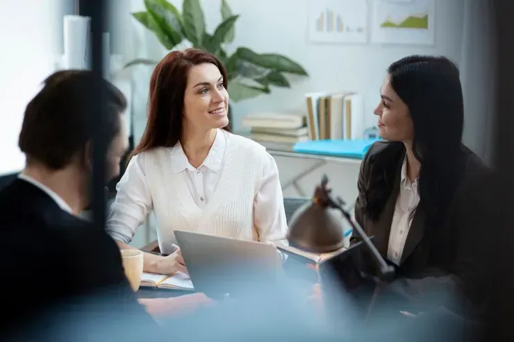 A group of people are sitting at a table talking to each other.