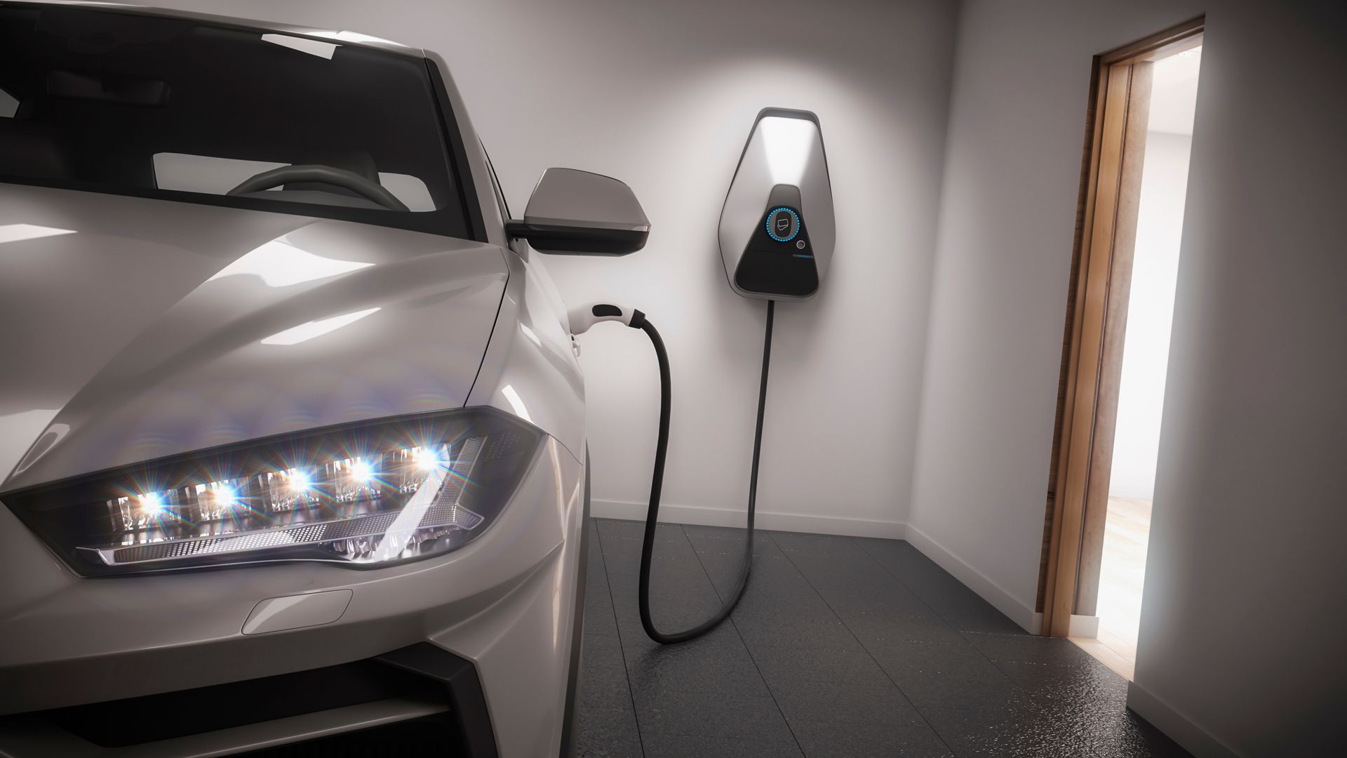 A silver electric car is parked inside a garage and is connected to a wall-mounted charging station.