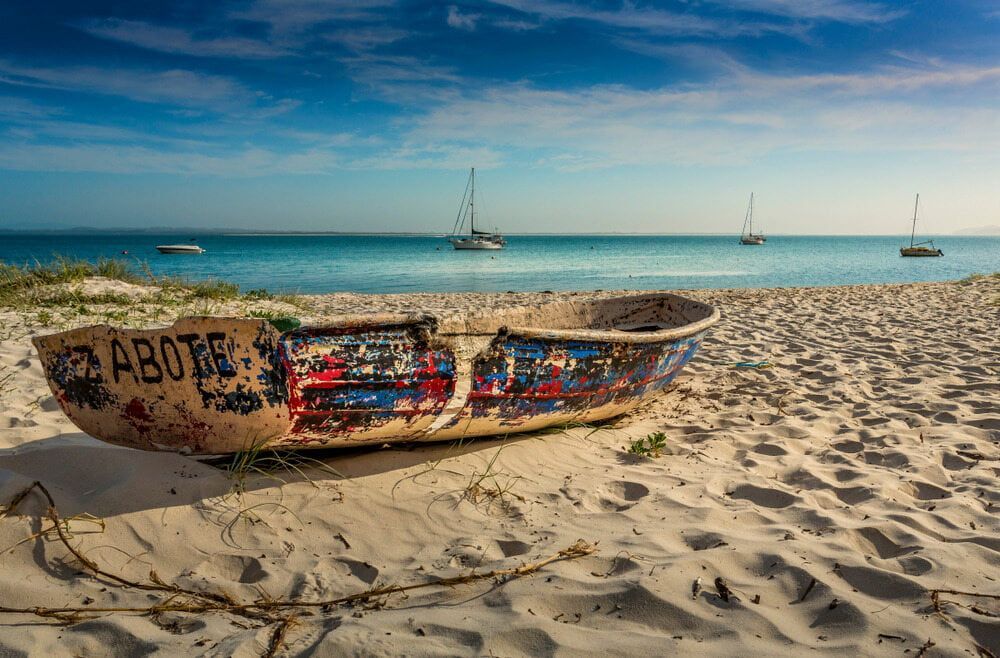 A Boat Is Sitting On A Sandy Beach Near The Ocean — The Kitchen & Bathroom Doctor in Corlette, NSW