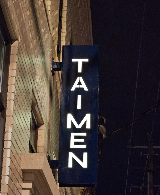 A sign on the side of a building that says tai-men