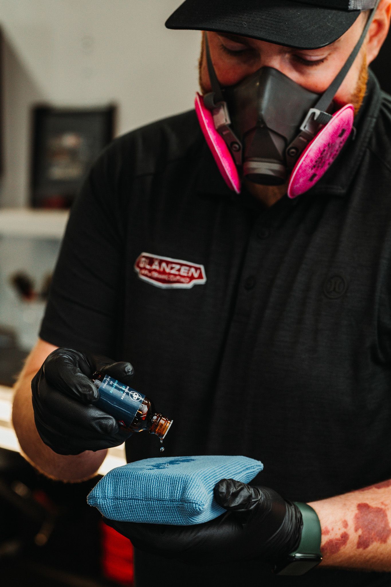 A man wearing a gas mask and gloves is holding a blue cloth.